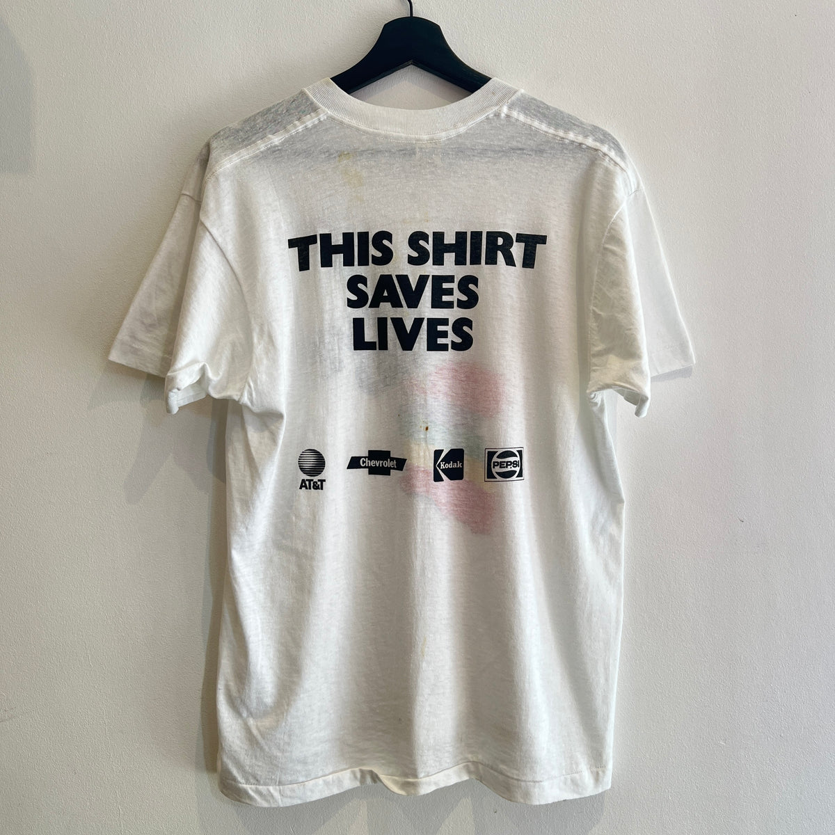 1985s Live Aid Logo T-Shirt with This Shirt Saves Lives Letters Print