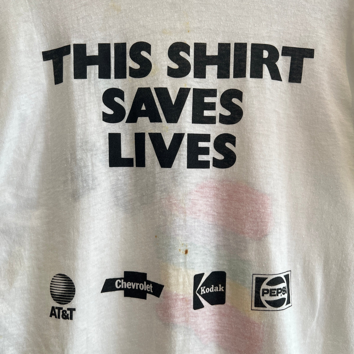 1985s Live Aid Logo T-Shirt with This Shirt Saves Lives Letters Print